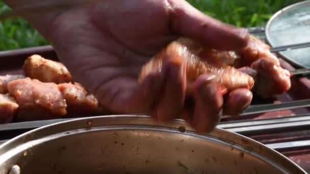 Брудна чоловіча рука бере сирий м'ясний шашлик і нанизує його на металеві шампури в негігієнічних умовах — стокове відео