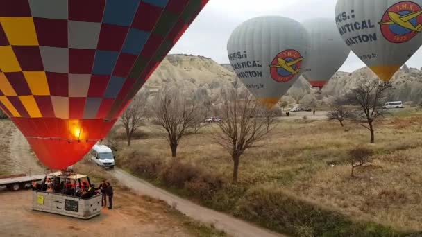 人々でいっぱいのカラフルな熱気球のバスケットとカッパドキアトルコの山の風景の上に風船を上げる — ストック動画