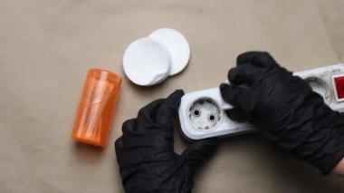 Siyah eldivenli eller kirli plastik eklenti prizini temizler. Elektrik genişleticisi temizleniyor