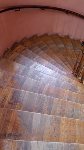 Velha escada em espiral de madeira com grades ornamentadas e degraus rasgados. Movimento lá em baixo — Vídeo de Stock