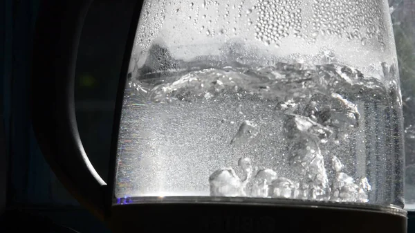 Bolhas borradas de água fervente em chaleira transparente velha à luz solar brilhante — Fotografia de Stock