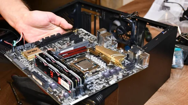 Soft focus male hands hold motherboard mini-ITX with blurred hardware — Stock Photo, Image