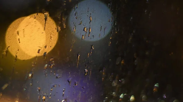 Gocce di pioggia sulla superficie della finestra sporca con sfondo luci bokeh — Foto Stock
