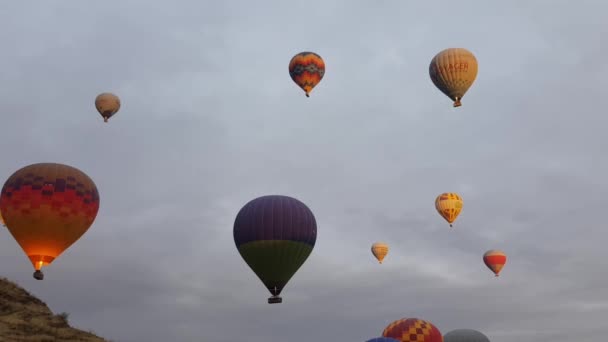 Kleurrijke heteluchtballonnen rijzen op en zweven in de lucht boven het berglandschap in Cappadocia Turkije — Stockvideo