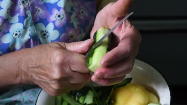 Крупним планом похилого віку 80-х жіночі руки вирізали огіркові пілінги ножем — стокове відео