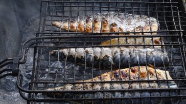 Izgara ızgarasının içinde ızgara ızgara ızgara ızgara ızgara ızgara ızgara ızgarası var. Açık hava barbekü ızgarası kullanarak yerel deniz balığı hazırlığı