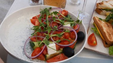 Taze sebze salatası ve kulüp sandviçleriyle kapanış masası. Kumsalda güneşli bir günde yemek servisi.