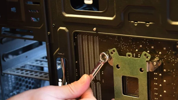 Male hand with metal wrench fix nut on bolt at computer motherboard — Stock Photo, Image