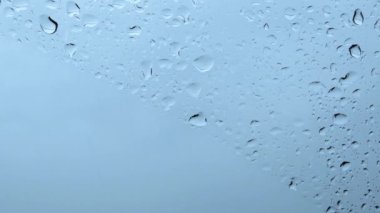 Damlayan damlalar ve kopyalama alanı ile ıslak camın açık mavi arkaplanı