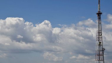 Yüksek mavi gökyüzü ve yüzen beyaz bulutlar ile iletişim kulesi