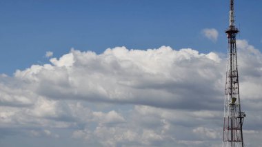 Yüksek mavi gökyüzü ve yüzen beyaz bulutlar ile iletişim kulesi