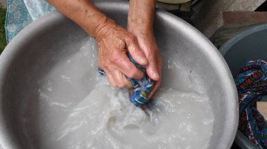 Kırış kırış ellerle çamaşır yıkamak ve 80 yaşında yaşlı bir kadının cildine sahip olmak.