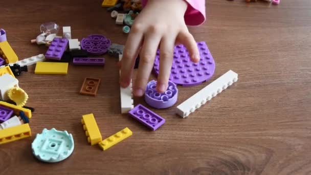 Dłonie malucha bierze małe klocki Lego i zabawki podczas gry Lego — Wideo stockowe