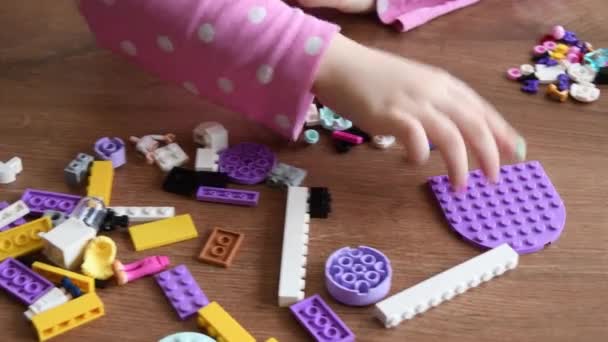 Toddler girl fingers touch and rotate tiny Lego bricks and toys playing Lego games — Stock Video