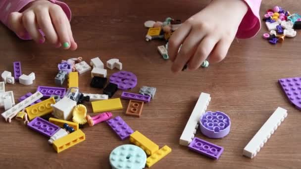 Маленькая девочка руки коснуться и вращать крошечные кирпичи Лего и игрушки, играя в игры Лего — стоковое видео