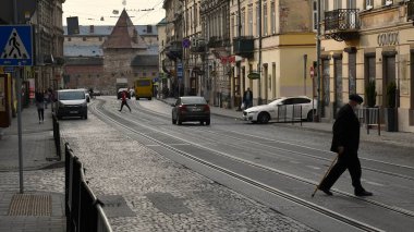 Maskeli yaşlı adam Covid-19 salgını sırasında eski Lviv şehir sokağından geçiyor.
