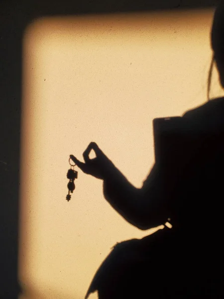 Elegant gesture of female hand with keys, shadow on wall