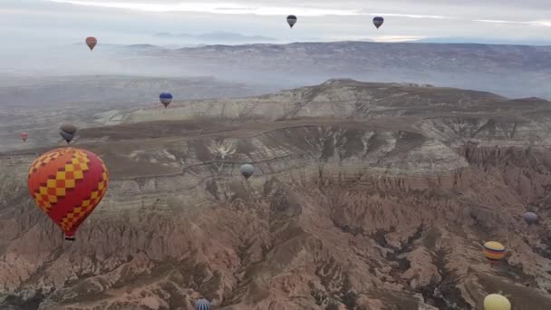 Vörös hőlégballon és sok színes léggömb lebeg át hegyvidéki táj Cappadocia Törökország — Stock videók