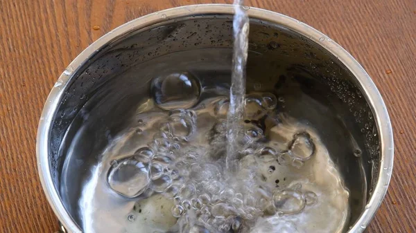 Temiz su, küçük bıldırcın yumurtalarıyla metal kaba dökülüyor. Kaynamaya hazır.