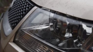 Yağmur damlaları ve bulanık yansımalarla arabanın farlarına yaklaş