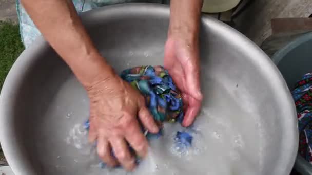 Γερασμένα ρυτιδιασμένα χέρια ηλικιωμένης γυναίκας που τσαλακώνει μπλε ύφασμα ενώ πλένει το χέρι — Αρχείο Βίντεο