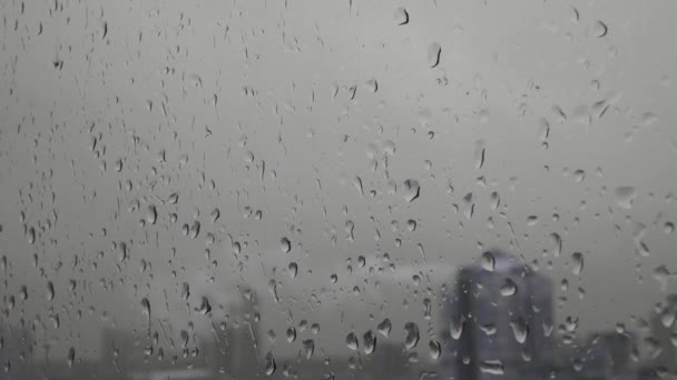 창문 뒤에 물방울 이 뚝뚝 떨어지고 도시 경관 이 흐릿 한 젖은 유리의 단조 로운 배경 — 비디오