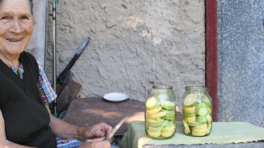 Kabak konservesini hazırlarken neşeli yaşlı kadın gülümsüyor.