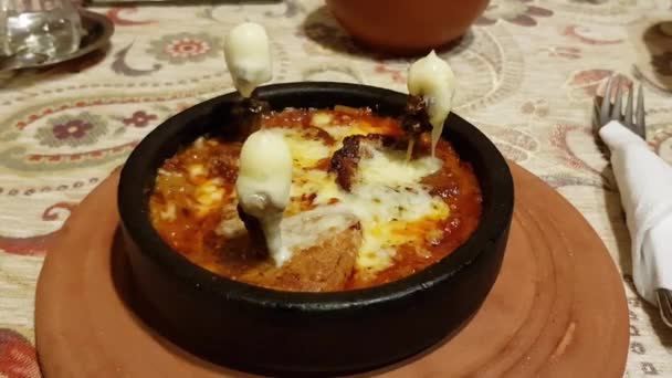 Salsa de tomate hirviendo de estofado tradicional de cordero turco con queso caliente derretido — Vídeo de stock