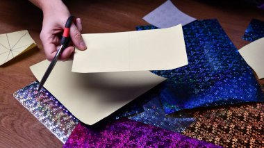 Kadın eli makas ve sarı el işi kâğıdı. Bulanık arkaplan üzerine simli kağıtlar hazırlama hobisi