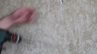 Erkek eller, duvarda delik açmak için matkapla çalışır. Ev geliştirme