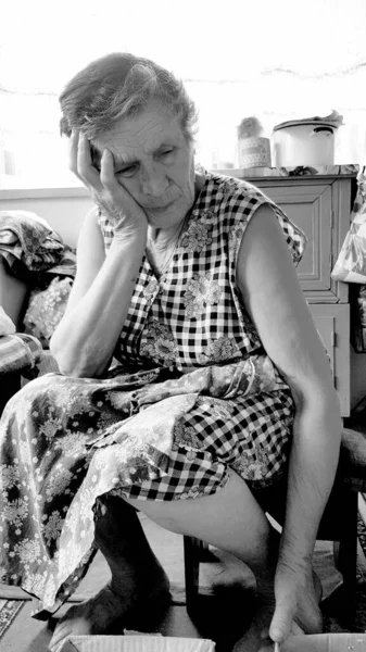 Mulher idosa perturbada segura a cabeça com a mão. Foto conceitual preto e branco — Fotografia de Stock