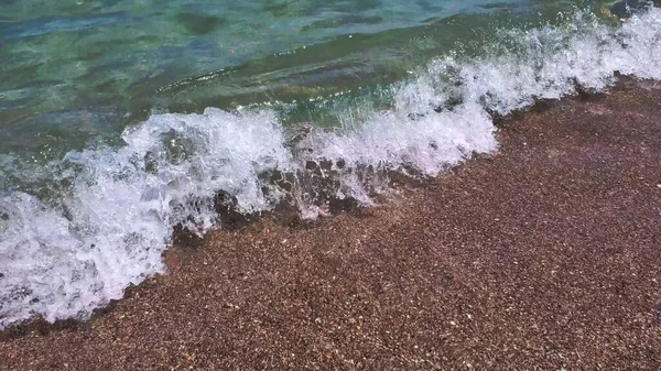 Deniz köpüğü ve berrak su deniz dalgalarında kumsala akıyor. — Stok fotoğraf