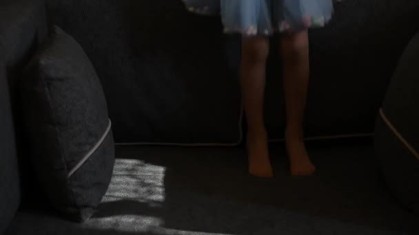 Bosé nohy dítěte skákajícího na gauči s polštáři doma. Zpomalený pohyb — Stock video
