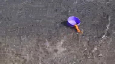 Güneşli yaz gününde deniz sörfü suyunda kayıp bir oyuncak. El, sudan plastik oyuncak kap yakalar.