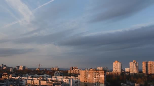 석양 빛으로 도시 경관을 덮고 있는 푸른 하늘에 떠 있는 회색 솜털 구름 — 비디오