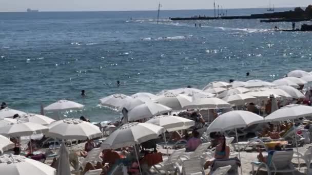 日光浴や水泳の人々とビーチで白いパラソルと夏の海 — ストック動画