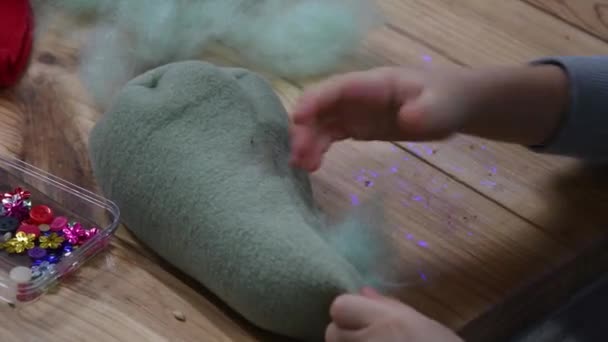 Kid handen vulling van handgemaakte vilt speelgoed met behulp van groene sintepon katoen vulling — Stockvideo