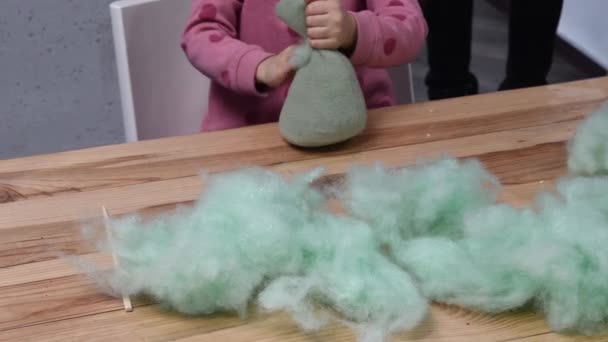 Kid girl hands stuffing handcrafted felt toy using green sintepon cotton filling — Stock Video