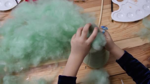 POV kid girl hands stuffing handcrafted felt toy using green sintepon cotton filling — Stock Video