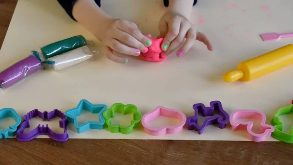Toddler hands playing colorful play tough with plastic molds and rolling pin — стоковое фото