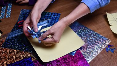 Kadınlar hobileri olan, parıldayan parlak kağıtlarla kar taneleri yapan eller.