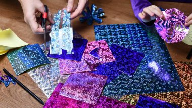 Anne ve çocuk, parıldayan parlak kağıtlarla kar taneleri hazırlayan hobi sahibi.