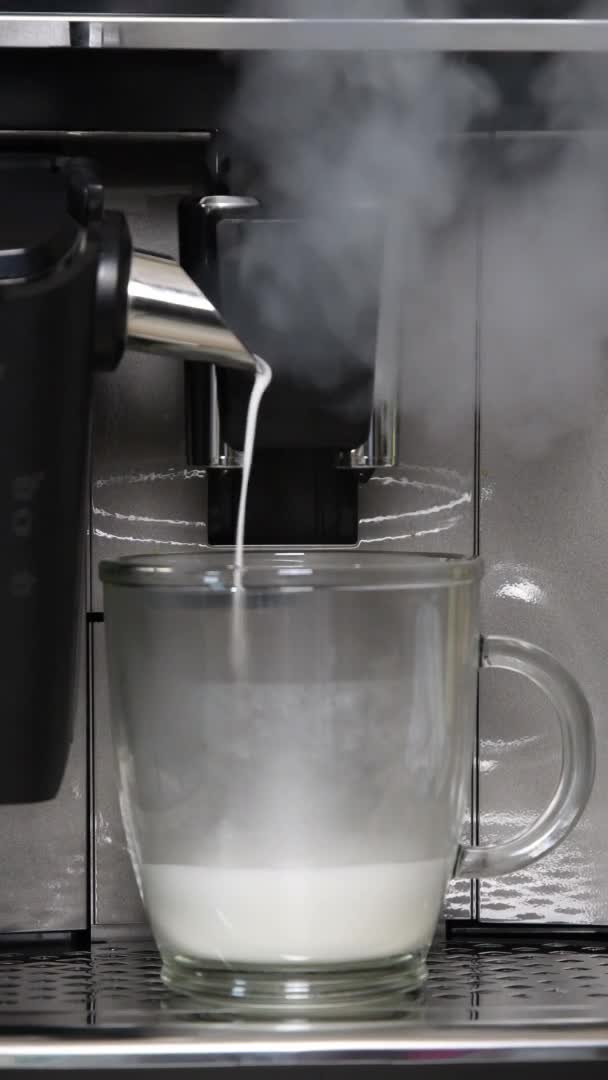 Pembuat kopi menuangkan susu panas dan espresso untuk menyiapkan kopi dengan buih susu — Stok Video