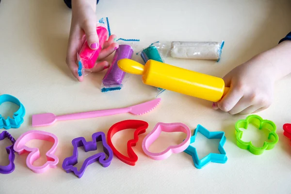 Девочка малыша руки играть красочные тесто с пластиковыми формами и желтый скалка — стоковое фото