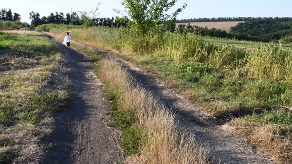 Country road at plain summer landscape with running girl silhouette — Stock Photo, Image