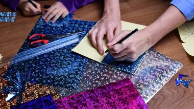 Anne ve çocuk, parlak renkli kağıtlar ve kalemlerle hobi olarak el sanatları yapıyor.