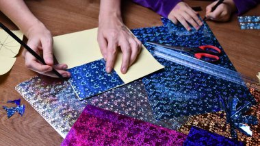 Anne ve çocuk, parlak renkli kağıtlar ve kalemlerle hobi olarak el sanatları yapıyor.