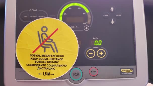 Keep social distance warning sticker on blinking digital display of treadmill gym equipment — Stock Video