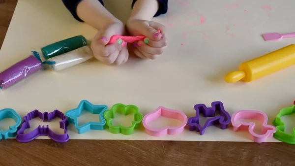 Toddler hands playing colorful play tough with plastic molds and rolling pin — стоковое фото