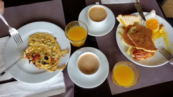 Time lapse personas comiendo con cuchillos y tenedores de platos llenos y beber jugo de naranja y café de la mañana — Vídeos de Stock